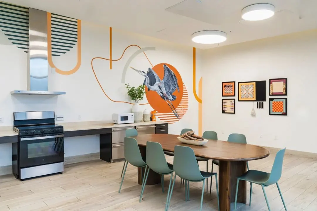 Community kitchen with a long wood dining table at Main Street Apartments